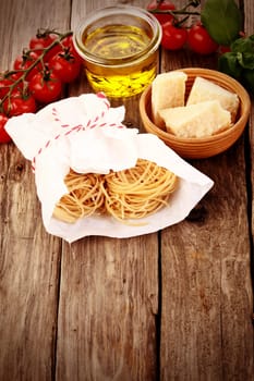 Close up Fresh Pasta Wrapped on White Paper with Other Ingredients, Tomatoes, Olive Oil and Cheese, on Vintage Wooden Table