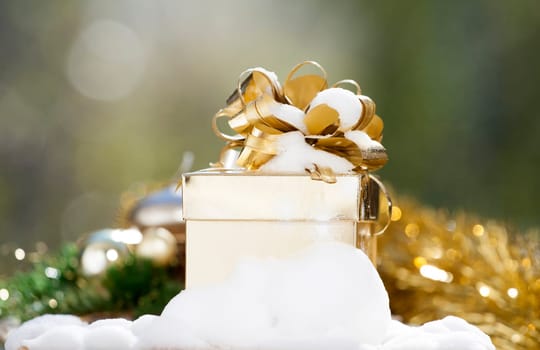 Golden Christmas background with present box on snow