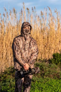 Naturalist photographer in action, with camouflage and camera, in the wilderness.