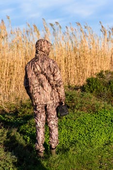 Naturalist photographer in action, with camouflage and camera, in the wilderness.