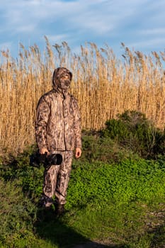 Naturalist photographer in action, with camouflage and camera, in the wilderness.