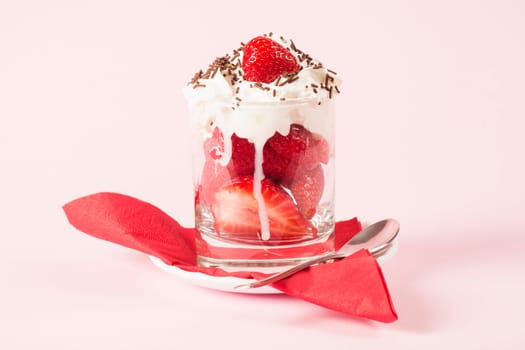 Sweet dessert from fresh strawberry fruit and whipped cream with chocolate crumbles on rose background.