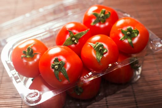 Beautiful red ripe tomatoes are in transparent plastic package, agriculture and food industry.