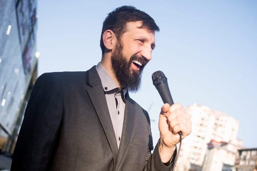 The smiling TV reporter is talking in microphone at the street.