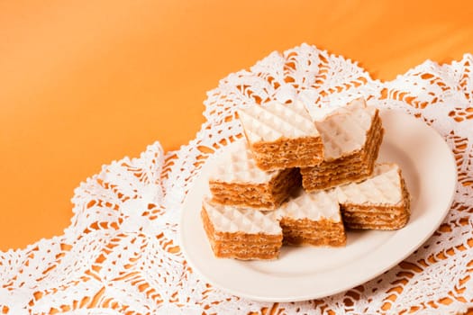 Filled wafer cake sweet dessert is on plate on orange background.