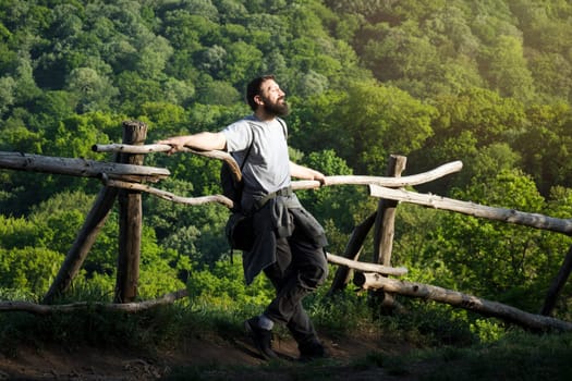 The bearded man is enjoying in nature on fresh air, sunlight and adventure on the trip.