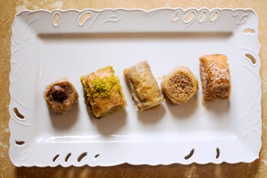 Five different taste of baklava, traditional Turkish dessert on white plate.
