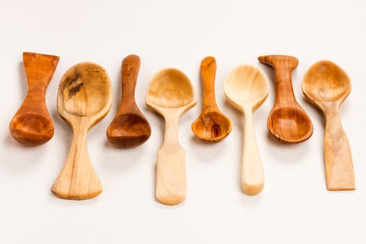 Different handmade wooden spoons are on white background.