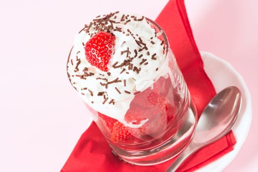 Sweet dessert from fresh strawberry fruit and whipped cream with chocolate crumbles on rose background.