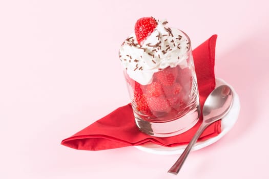 Sweet dessert from fresh strawberry fruit and whipped cream with chocolate crumbles on rose background.