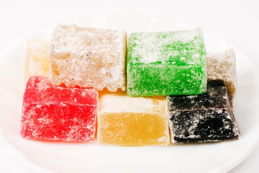 Colorful Turkish delight with different taste are on white plate on white background.