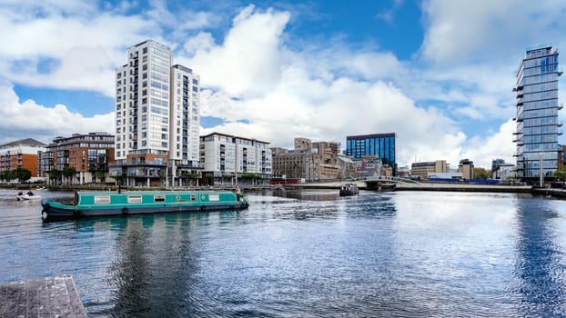 Cityscape of Dublin Docklands and river Liffey with modern buildings and barge on river. Republic of Ireland