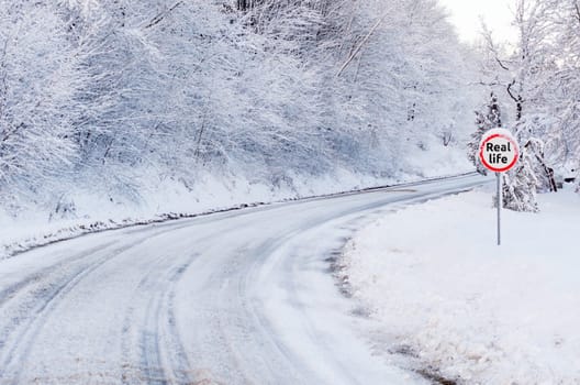 Snow tracks on a country road and road sing showing real life.