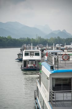Guilin, China - August 2019 : Sightseeing boats full of tourists departing on a trip on the magnificent Li river from Guilin to Yangshuo