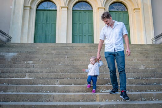 father and daughter go down the stairs and hold hands