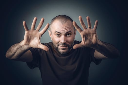 studio portrait of a man in a shirt with open hand position as if he were performing magic.