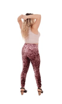 A young beautiful woman standing with her hands behind her head.from the back in tights, isolated for white background.