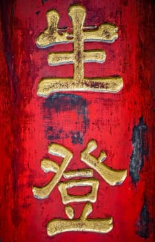 Golden chinese writing characters on a red wall background in the Wenshu Monastery, Chengdu, Sichuan Province, China