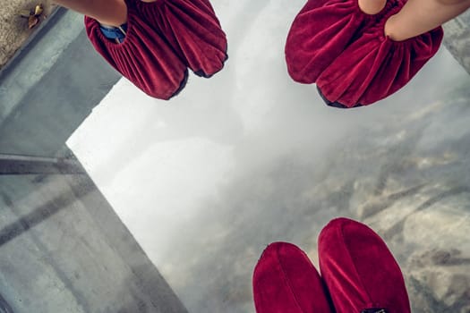 Feet of a family wearing in shoe covers while standing on glass pathway in Tianmenshan nature park, Zhangjiajie, China