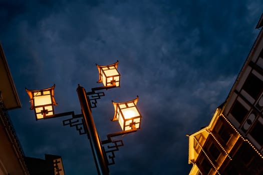 Brightly lit lamppost on the street in Wulingyuan after dusk at night, Hunan Province, China