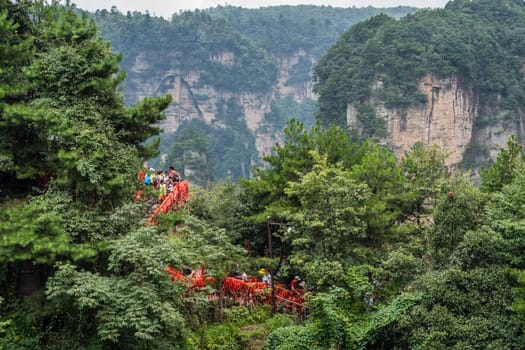 Zhangjiajie, China - August 2019 : Tourists on a scenic walking path to the viewpoints of the Greatest Natural Bridge also known as Tian Qiao Sky Bridge, Avatar mountains nature park, Zhangjiajie