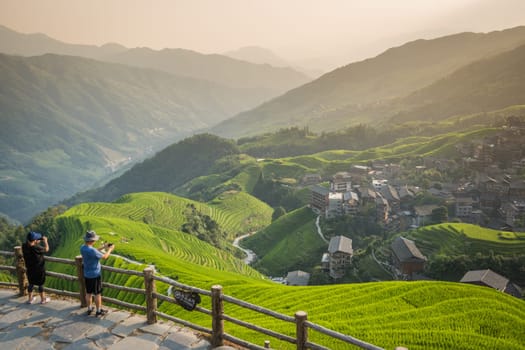 Pingan, China -  August 2019 : Group of tourists standing on a Nine Dragons and Five tigers viewpoint and admiring cascading layered Longji Rice Terraces, Pingan village, northern Guilin, Guangxi Zhuang Autonomous Region, Guangxi Province