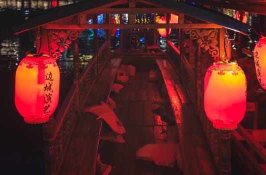 Feng Huang, China -  August 2019 : Red, yellow and orange lanterns hanging on the old historic wooden tourist boats in Feng huang Old Town