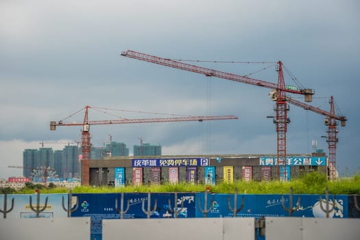 Zigong, China -  July 2019 : Tall cranes on a working construction building site, Sichuan Province