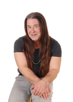 A happy indigenous man sitting for a portrait image on a chair with.his long brunette hair, isolated for white background.
