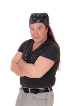 A serious looking middle age man in a black sweater standing with his .arms crossed and head scarf, isolated for white background.