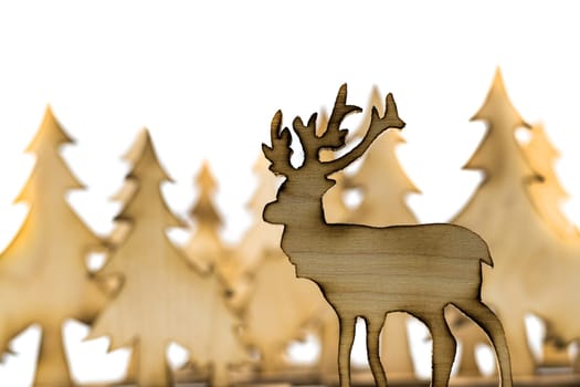 Cut out deer figure made of wood with dark edges and wooden fir trees isolated on white