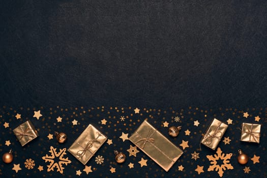 Festive composition with golden Christmas decorations and gold gift boxes on black textured background. Top view with copy space, Design element for greeting card, invitation, advertising, winter sale
