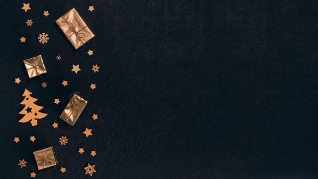 Festive composition with golden Christmas decorations and gold gift boxes on black textured background. Top view with copy space, Design element for greeting card, invitation, advertising, winter sale
