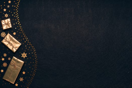 Festive composition with golden Christmas decorations and gold gift boxes on black textured background. Top view with copy space, Design element for greeting card, invitation, advertising, winter sale