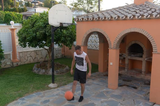 Young man plays basketball throws a ball into a basket in a jump