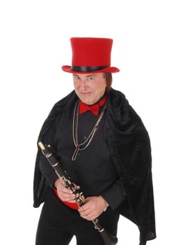 A middle age indigenous man holding his clarinet in a black outfit and.red hat and bow tie looking at camera, isolated for white background.