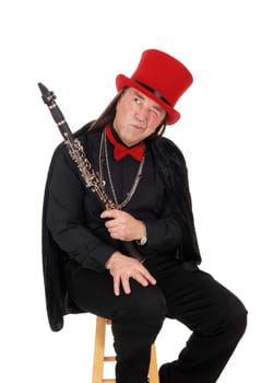 A middle age indigenous man holding his clarinet in a black outfit and.red hat and bow tie looking away, isolated for white background.