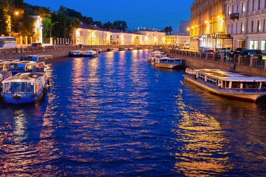 Night illuminated cityscape with boats at canal, Saint Petersburg, Russia