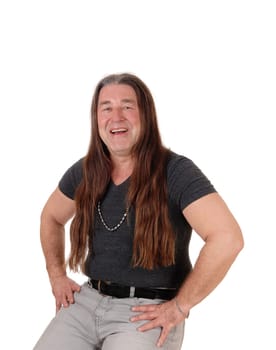 A happy indigenous man sitting for a portrait image on a chair with.his long brunette hair, isolated for white background.