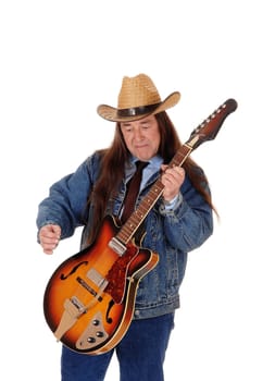 A handsome indigenous man in a jeans jacket, pants and a cowboy hat.standing and playing the guitar, isolated for white background.