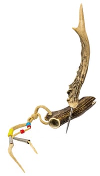 Sewing awl of the North American Indians made of stag horn with metal tip decorated with leather cords and glass beads isolated on white