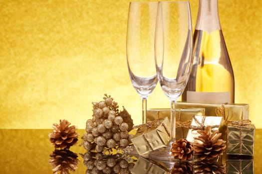 Golden Christmas ornaments, gift boxes, champagne bottle and empty champagne flutes on gold background. Christmas. New Year. Design element for greeting card, invitation, advertising