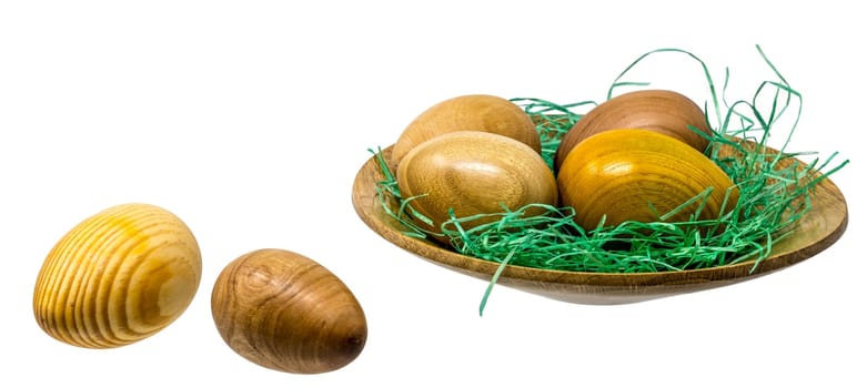 Hand-turned wooden eggs in a smal wooden bowl isolated on white