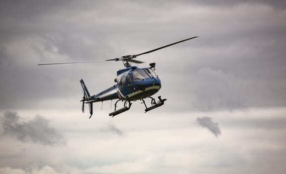 Blue helicopter in flight over a gray sky