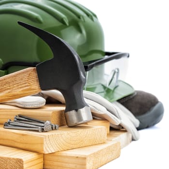 Close-up of a carpenter's hammer, helmet, goggles and protective gloves on a white background. Industry construction, work safety.