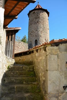 Old stairs to a round tower in a castle, with blue sky
