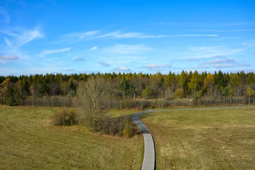 Green landscape from above, a path in the middle, with big meadow, trees and blue sky in the Rhön, Bavaria, Germany
