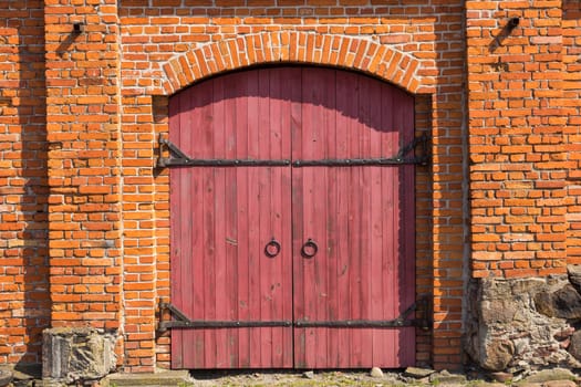 Red wooden door in red brick wall