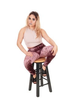 A young beautiful woman sitting on a chair in the studio.in a short sweater and tights, isolated for white background.