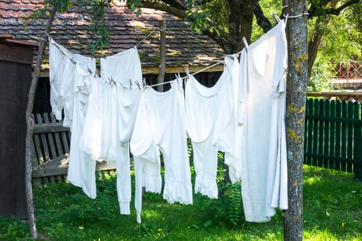 White vintage underwear hanging from a clothes line in a sunny summer garden